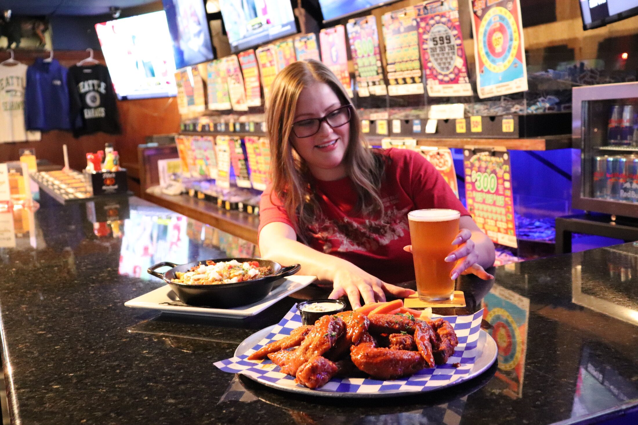 A bartender serving a basket of wings and a beer at Rooneys in Woodinville
