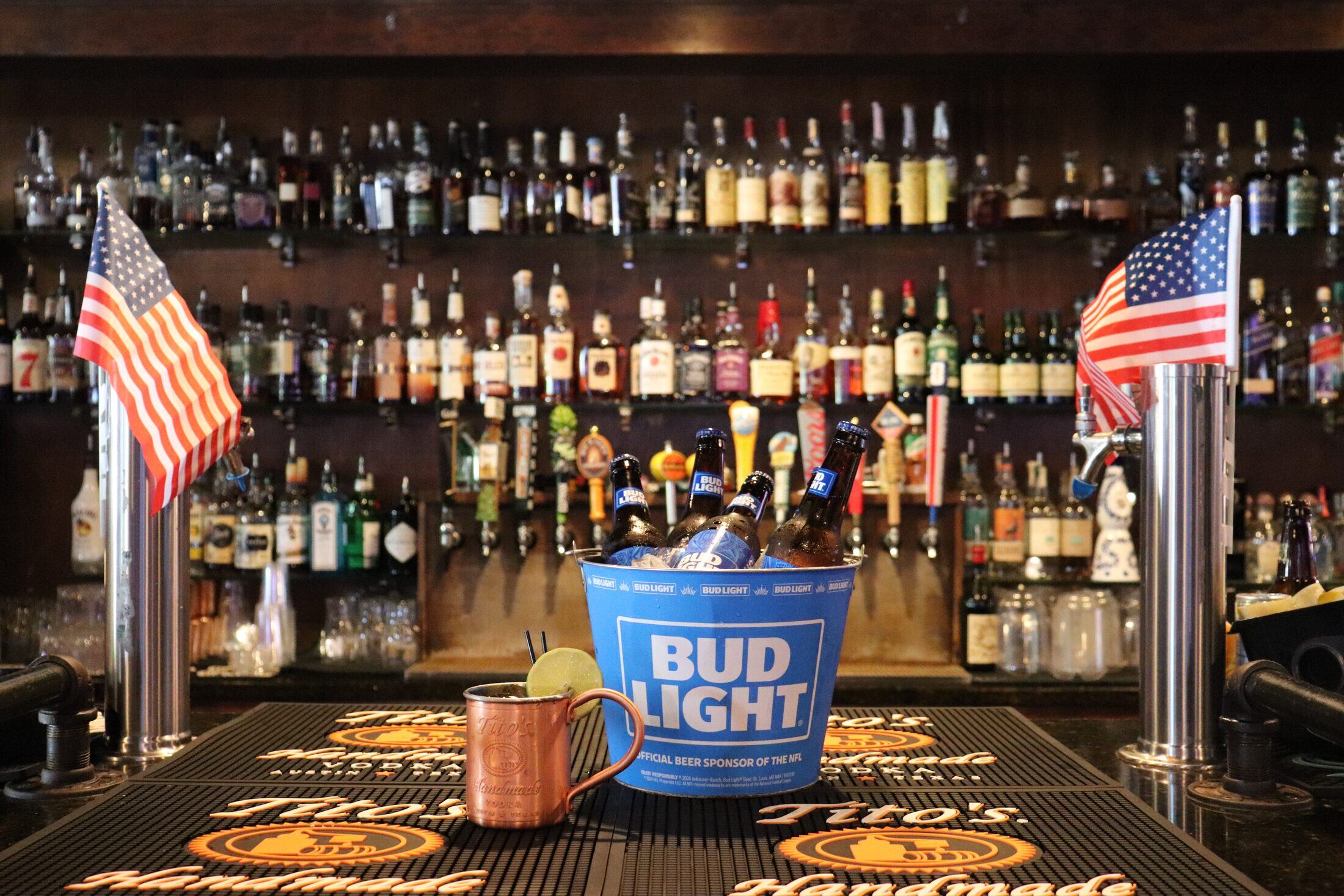A frosty bucket of beer and a Moscow mule on the bar at Rooneys, with the back-bar bottle wall behind