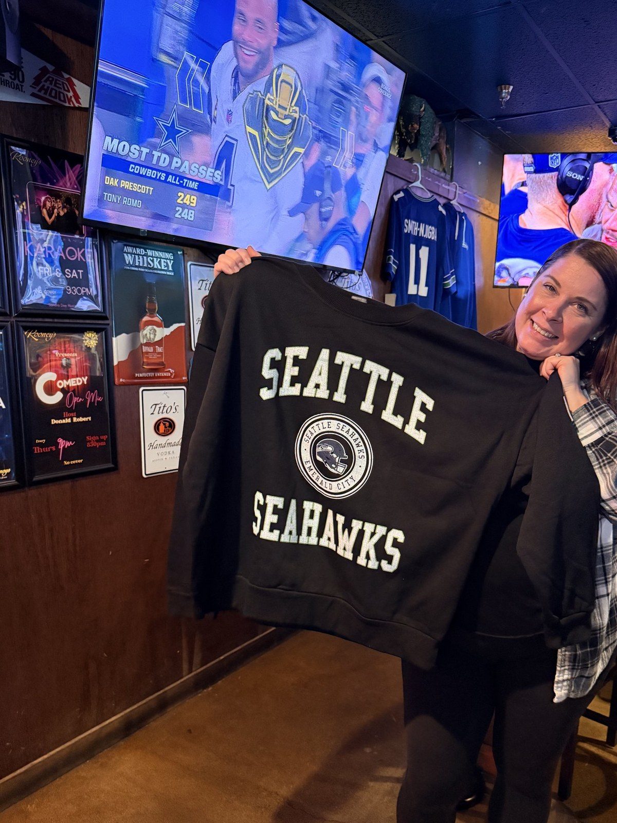 Amber holding up the black Seattle Seahawks crewneck she won at Rooneys Sports Bar in Woodinville