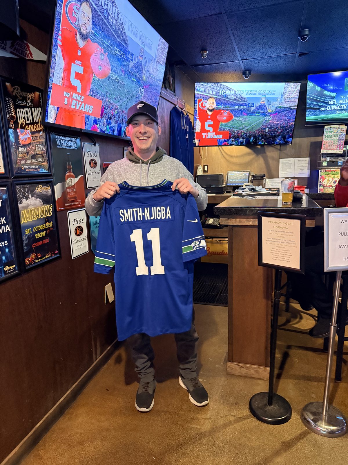 Brandon holding up the blue Seahawks Smith-Njigba number 11 jersey he won at Rooneys Sports Bar in Woodinville