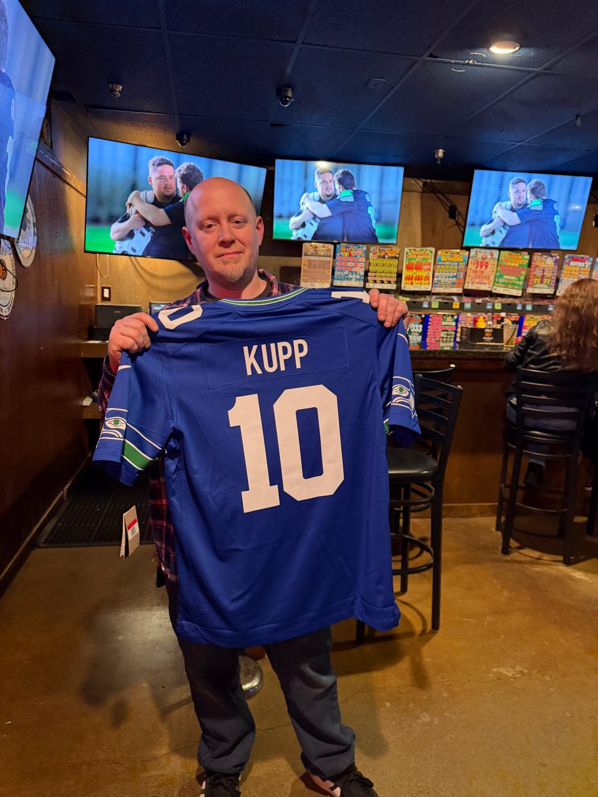 Eric holding up the royal blue Seahawks Kupp number 10 jersey he won at Rooneys Sports Bar in Woodinville